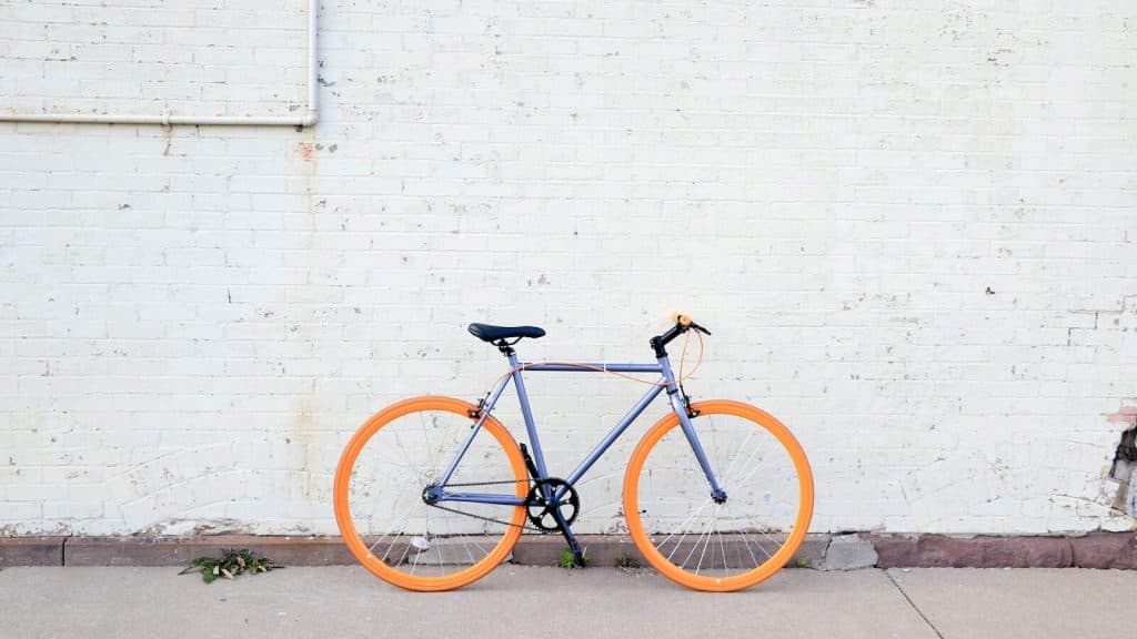 yellow and purple bicycle near white wall at daytime